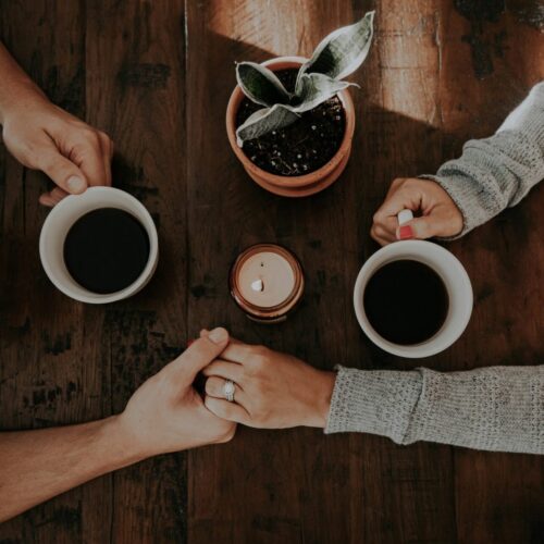 Couple holding hands across table, representing connection and healing in Philadelphia therapy