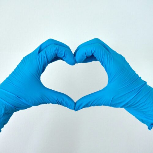 Two hands in medical gloves forming a heart shape, representing compassionate healthcare and healing from medical trauma through EMDR