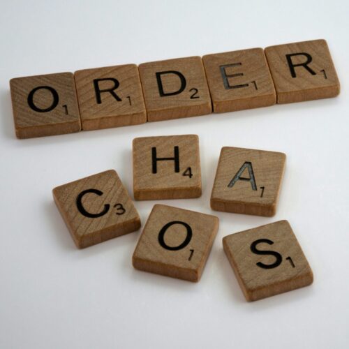 Scrabble tiles spelling 'CHAOS' scattered messily with 'ORDER' arranged neatly behind, representing the journey from Complex PTSD to healing