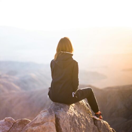 Confident woman sitting on mountain top, representing empowerment and new perspective after EMDR for childhood trauma