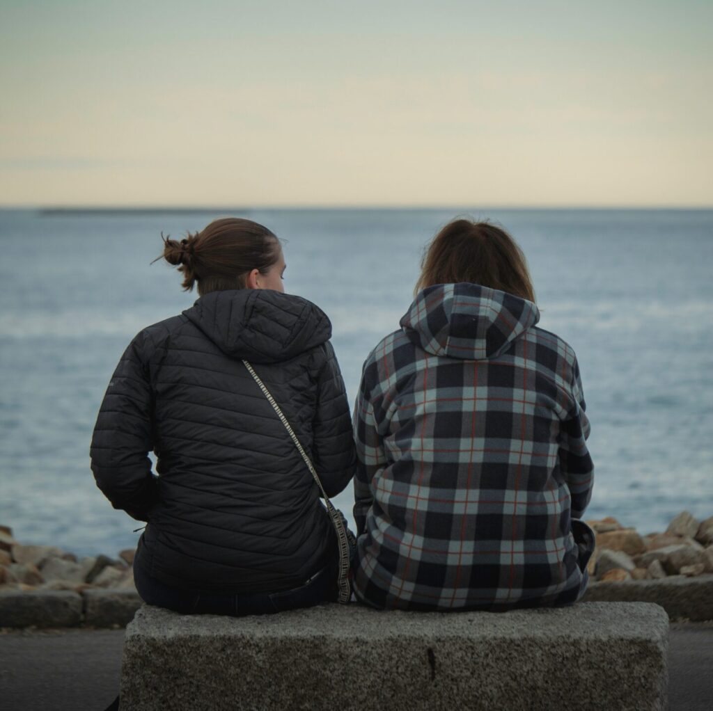 two people sitting by the water representing helping someone with depression